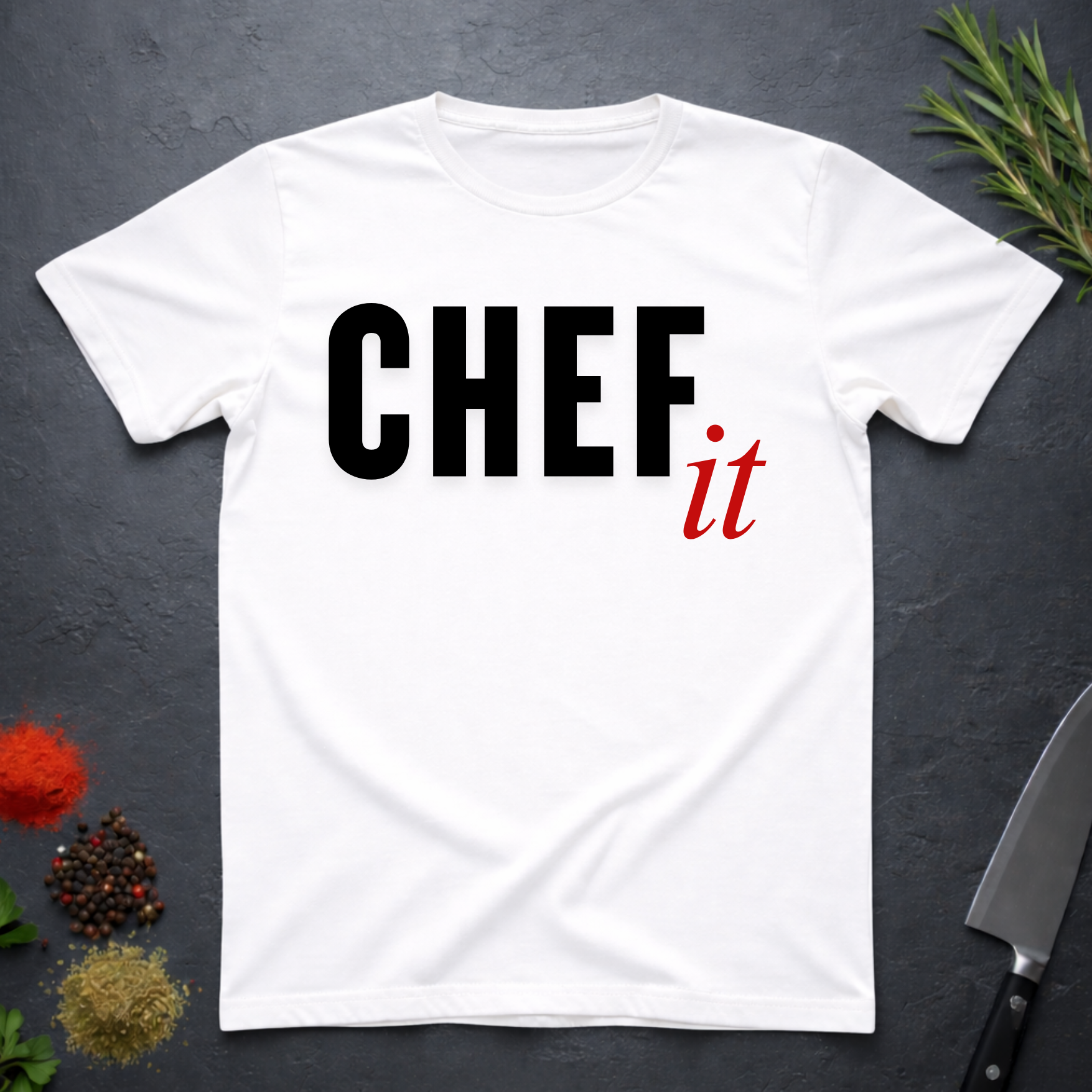 White t-shirt with 'CHEF it' text on a dark surface with kitchen items.