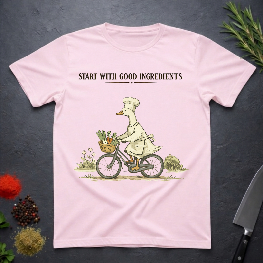 Light Pink t-shirt with a graphic of a goose chef riding a bike with vegetables in basket. Text "Start with Good Ingredients" above graphic. 