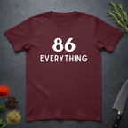 Maroon t-shirt with '86 EVERYTHING' text on a dark surface with decorative elements.
