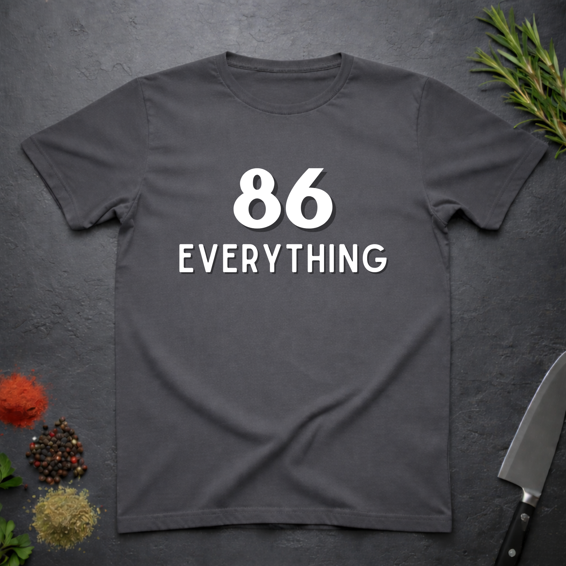 Charcoal Gray t-shirt with '86 Everything' text on a dark surface with decorative elements.