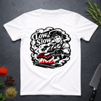 White t-shirt with 'Low & Slow' barbecue graphic on a dark surface with cooking tools and ingredients.