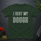 Forest Green t-shirt with 'I Rest My Dough' text on a dark surface with decorative elements.