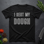Black t-shirt with 'I Rest My Dough' text on a dark surface with kitchen items.