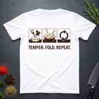 White t-shirt with chocolate-making diagram and text 'Temper. Fold. Repeat.' on a dark surface.