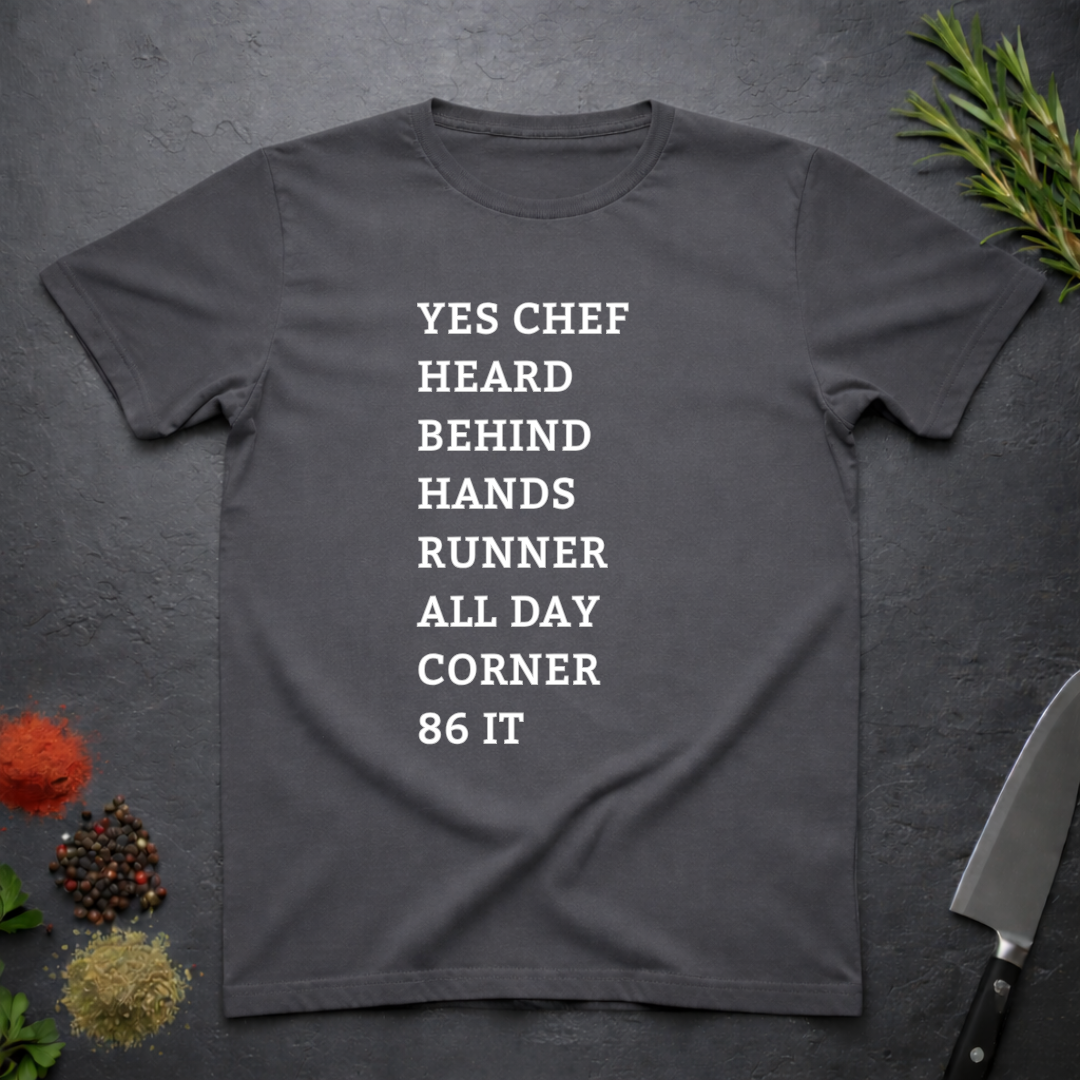 Charcoal Grey t-shirt with list of back of house kitchen words in white text on a dark surface with kitchen items.