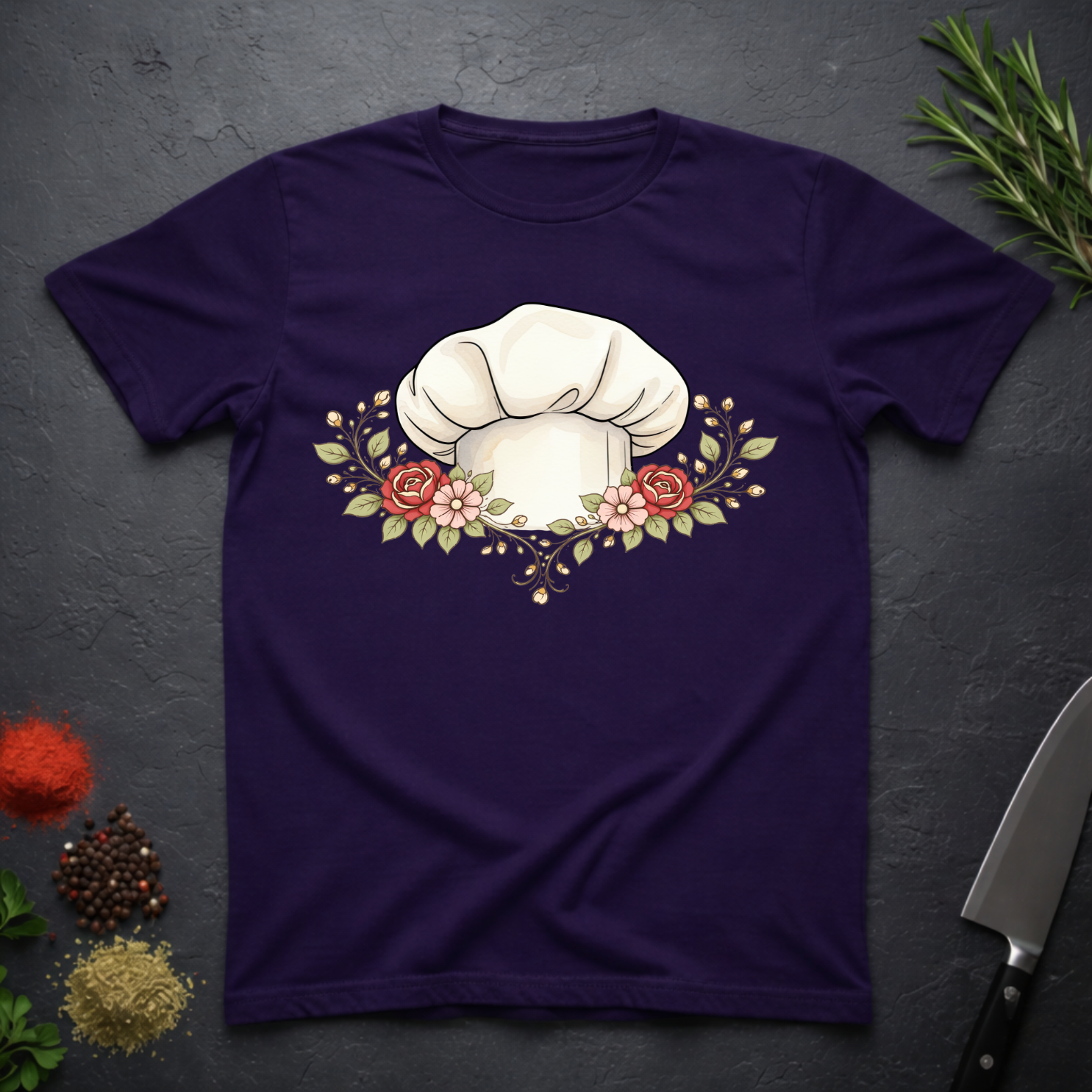 Amethyst Purple t-shirt with a chef's hat and floral design on a dark surface with kitchen items.
