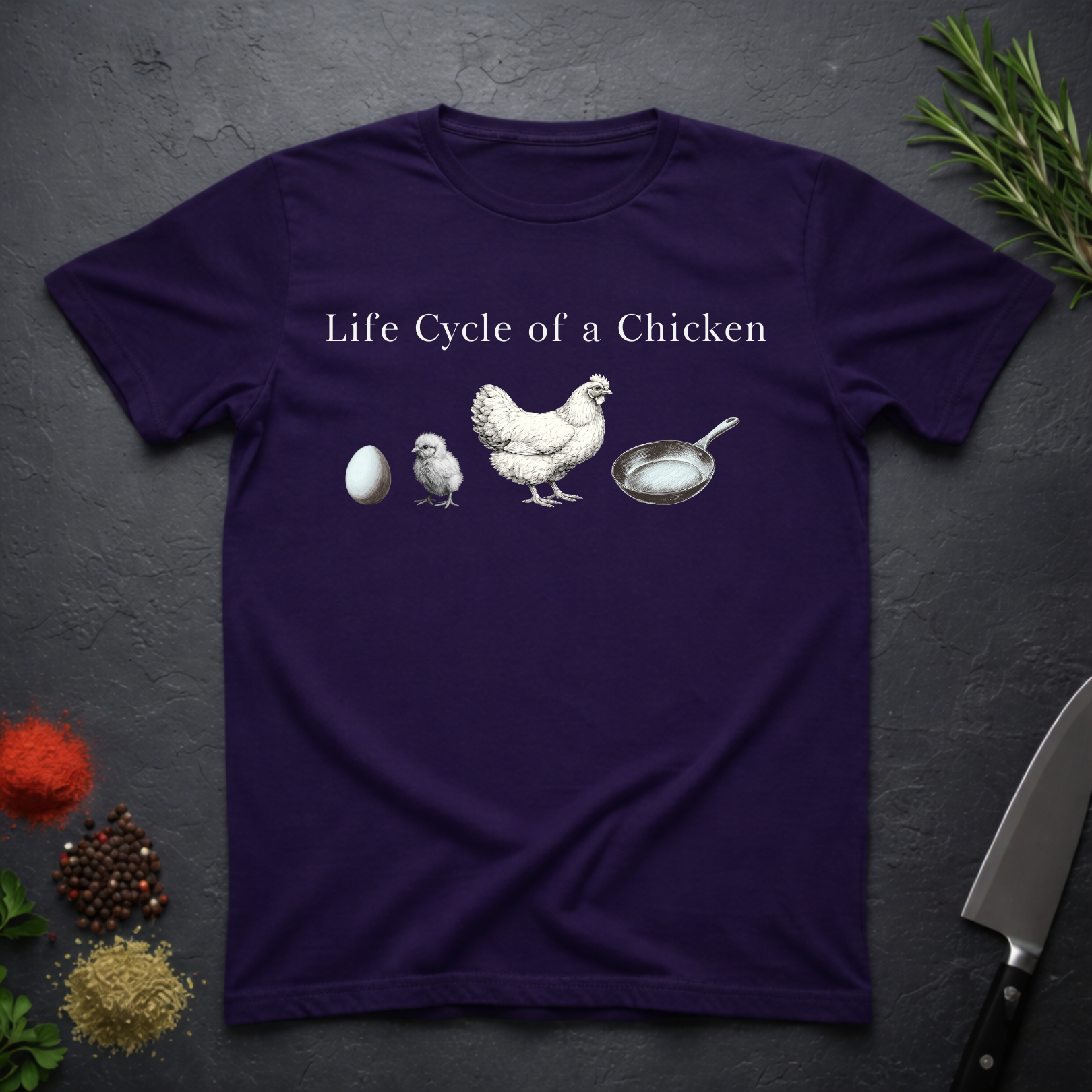 Amethyst purple t-shirt with text 'Life Cycle of a Chicken' and graphic of an egg, chick, hen, frying pan on a dark surface.
