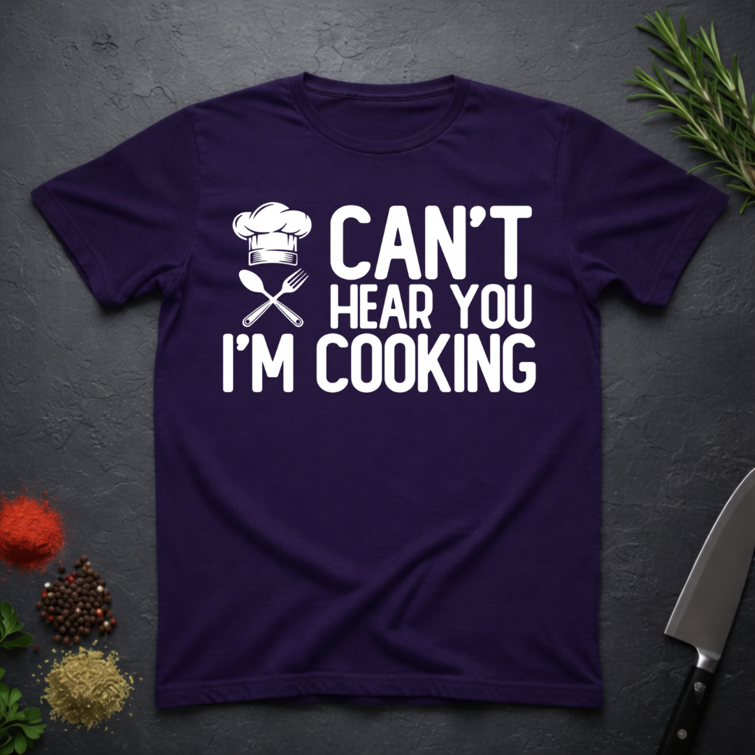 Amethyst Purple t-shirt with 'Can't Hear You I'm Cooking' text on a dark surface with kitchen items.
