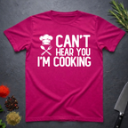 Antique Heliconia Pink t-shirt with 'Can't Hear You I'm Cooking' text on a dark surface with kitchen items.