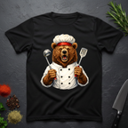 Black t-shirt with a grizzly bear chef holding utensils design on a dark surface.