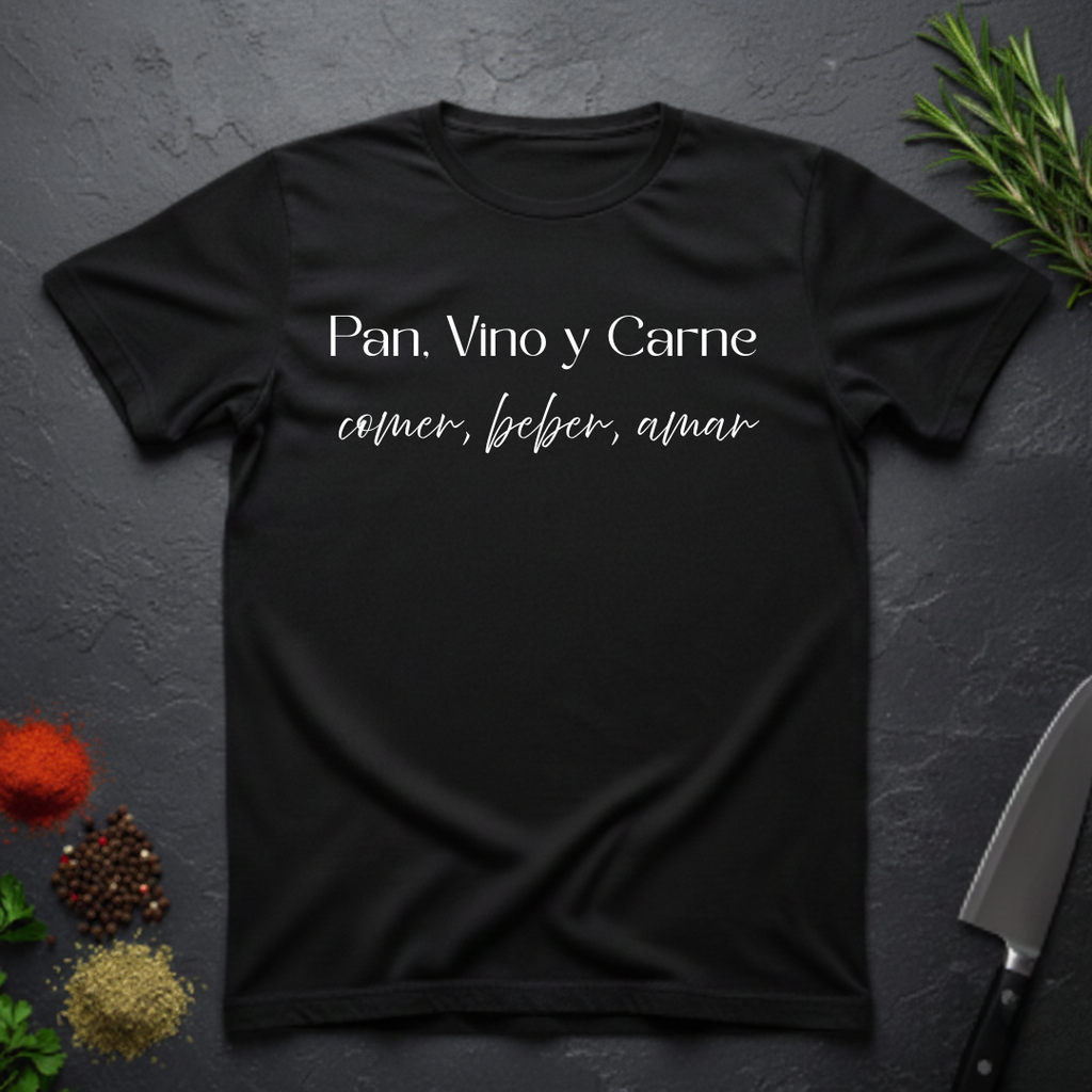 Black t-shirt with Spanish text "Pan, Vino y Carne" on a dark surface with decorative elements. 