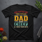 Black t-shirt with colorful text design "God Gifted me Two Titles, Dad and Chef" on a dark surface.