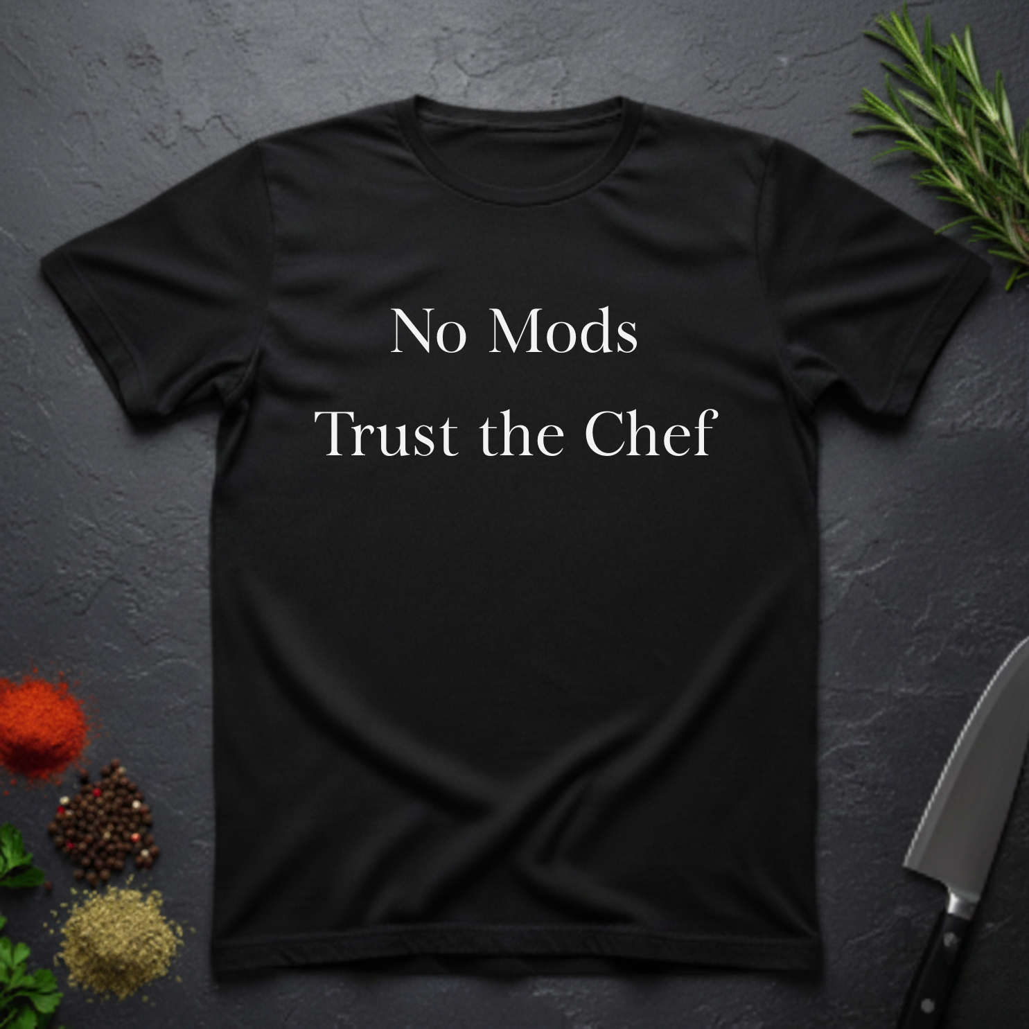 Black t-shirt with 'No Mods Trust the Chef' text on a dark surface with kitchen items.