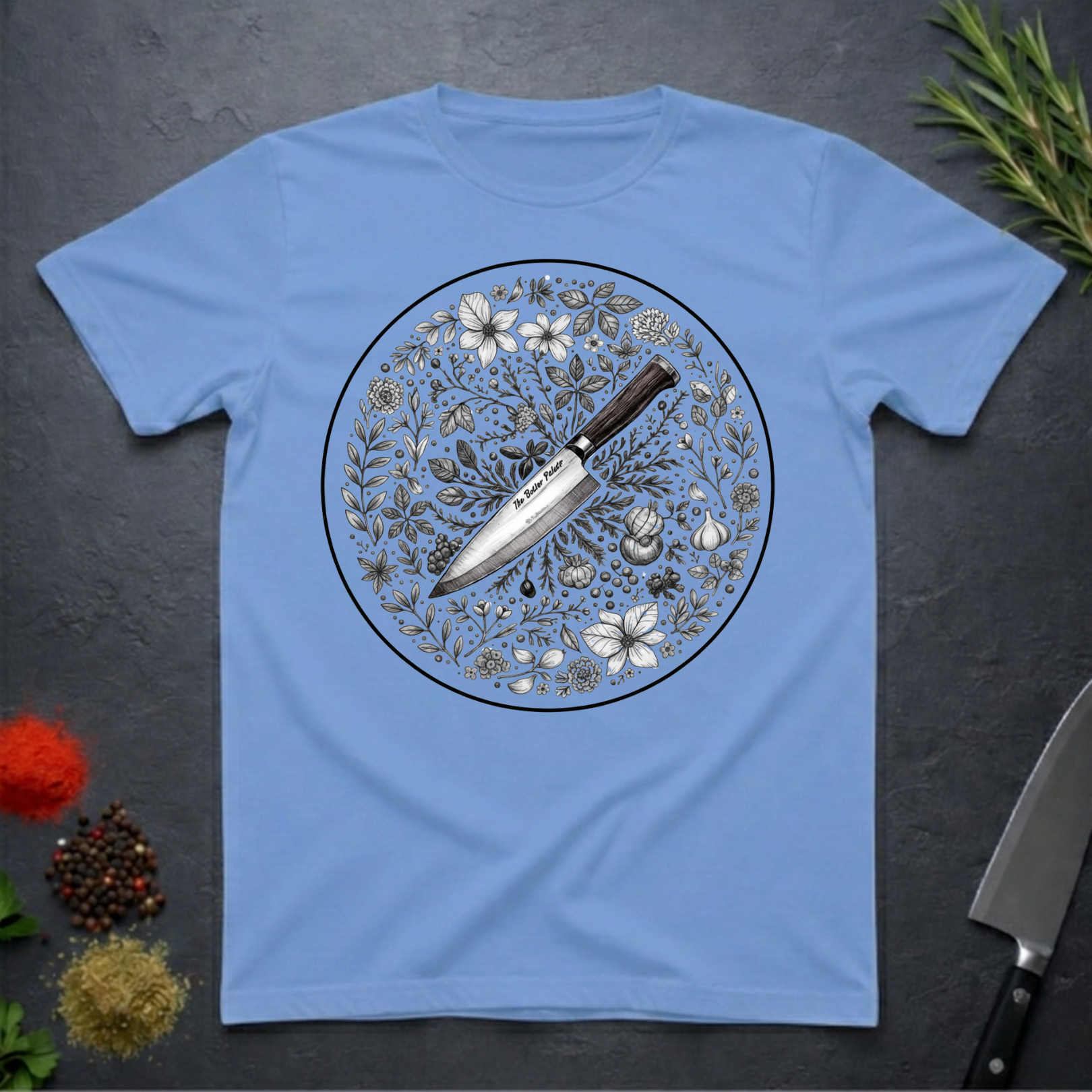 Carolina blue t-shirt with a circular floral and knife design on a dark surface.