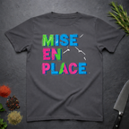 Charcoal Gray t-shirt with colorful fractured 'MISE EN PLACE' text on a dark surface.