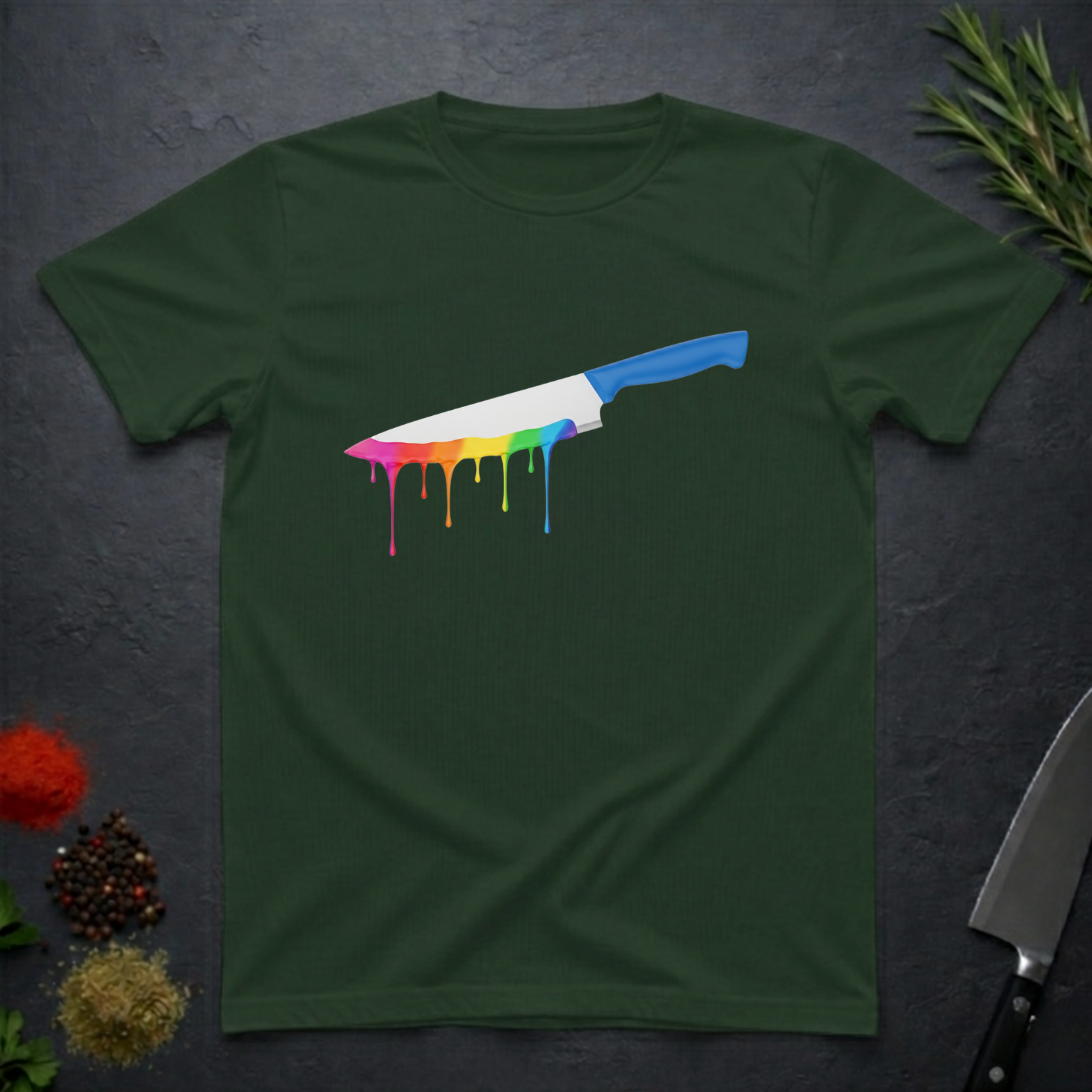 Forest green t-shirt with a chef's knife with rainbow colored drip design on a dark surface.