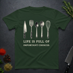 Forest green t-shirt with kitchen utensil graphics and text "Life is Full of Important Choices" on a dark surface.