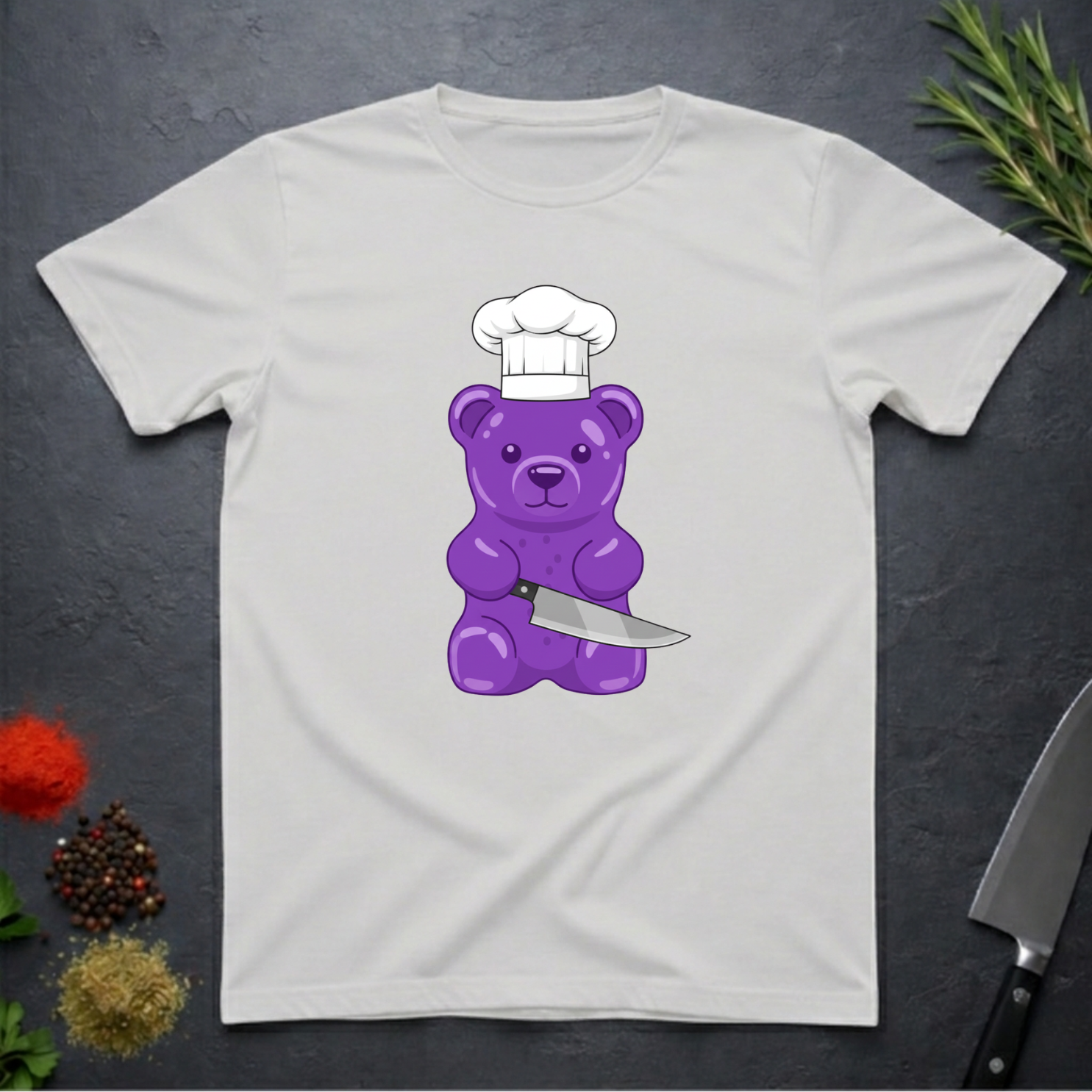 Ice Grey t-shirt with a purple gummy bear wearing a chef's hat and holding a knife on a dark surface.