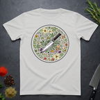 Ice grey t-shirt with a circular knife and colored floral design on a dark surface.