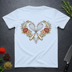 light blue t-shirt with a design of crossed kitchen utensils and flowers on a dark surface.
