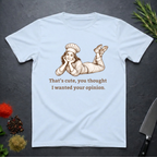 Light blue t-shirt with a graphic of a woman in a chef's outfit and text "That's cute, you thought I wanted your opinion." On a dark surface.