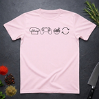 Light pink t-shirt with black icons of chef hat, game remote, ramen bowl and repeat symbol on a dark surface.
