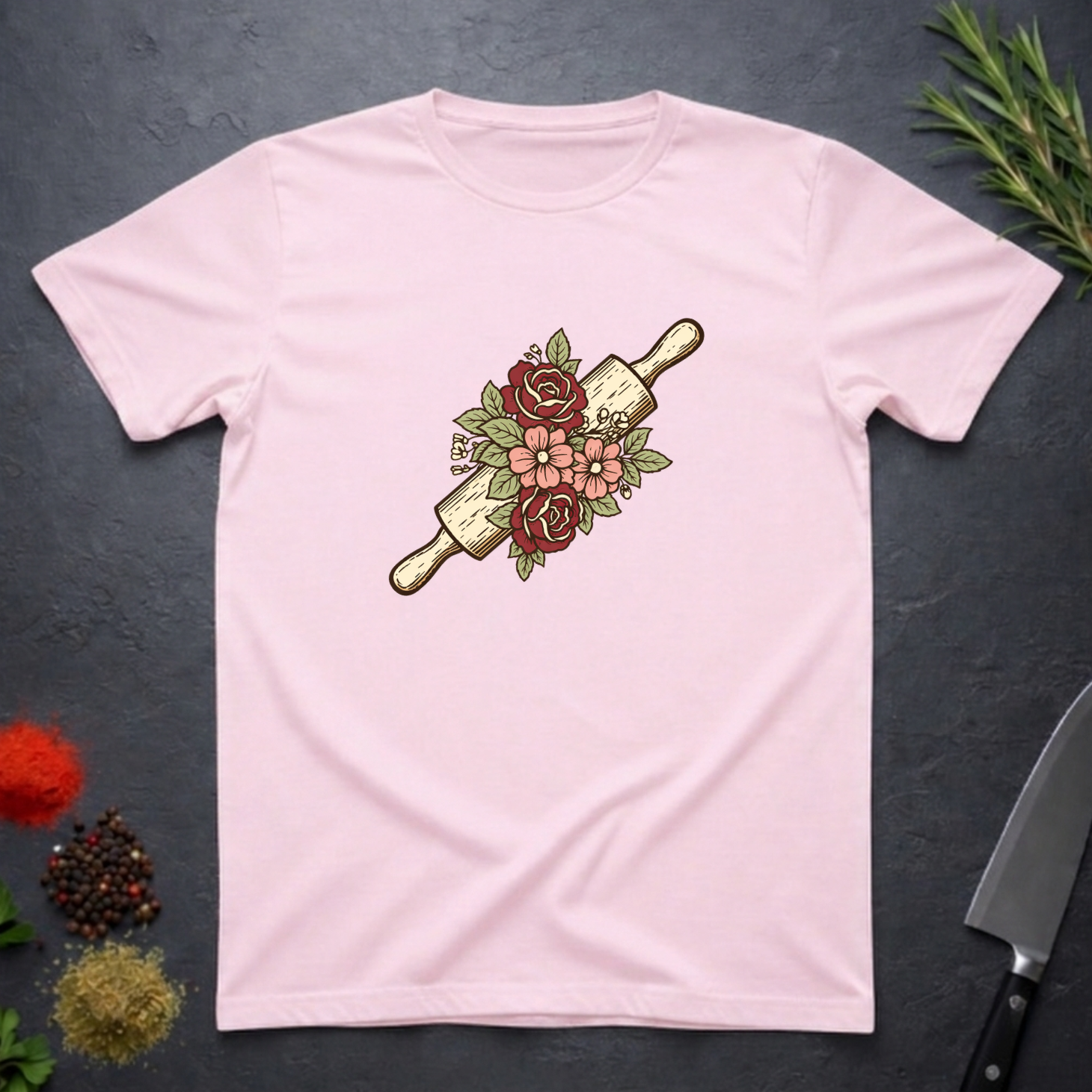 Light Pink t-shirt with a rolling pin and floral design on a dark surface.