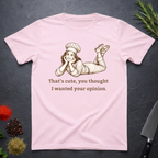 Light pink t-shirt with a graphic of a woman in a chef's outfit and text "That's cute, you thought I wanted your opinion." On a dark surface.