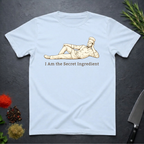 Light Blue t-shirt with a graphic of a chef lying on his side and text 'I Am the Secret Ingredient' on a dark surface with kitchen items.