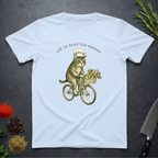 Light blue t-shirt with a graphic of a cat riding a bicycle and text 'off to feed the masses' on a dark surface.