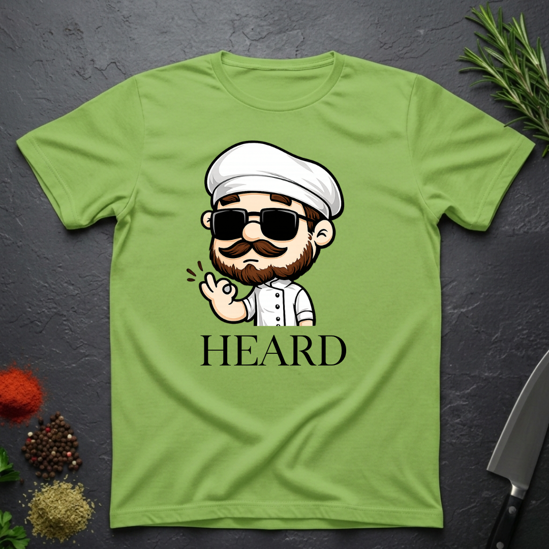 Lime Green t-shirt with a cartoon character chef and 'HEARD' text on a dark surface.