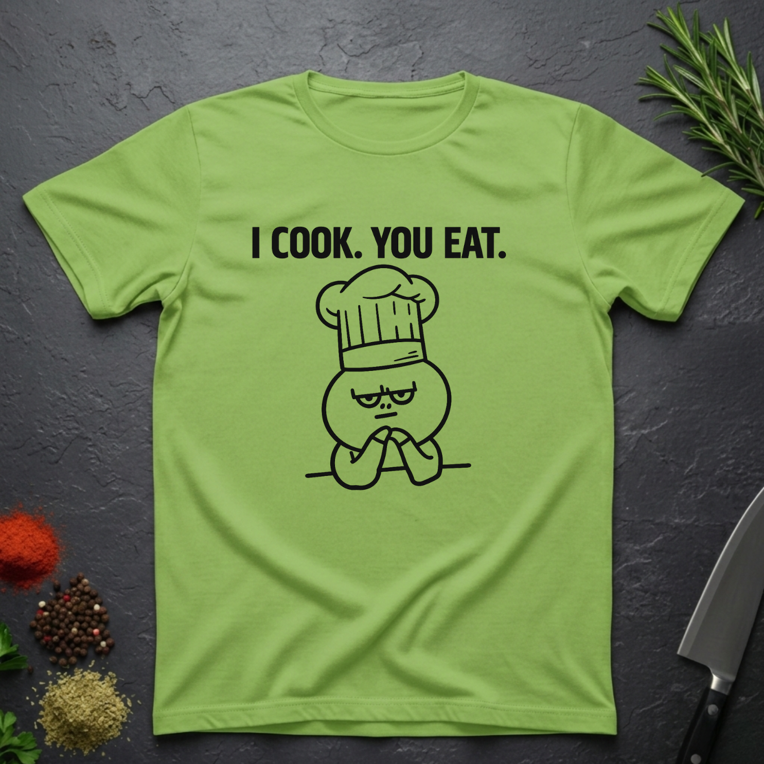 Lime Green t-shirt with 'I Cook. You Eat.' graphic on a dark surface with kitchen items.
