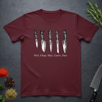 Maroon t-shirt with knife graphic and text on a dark surface with kitchen items.