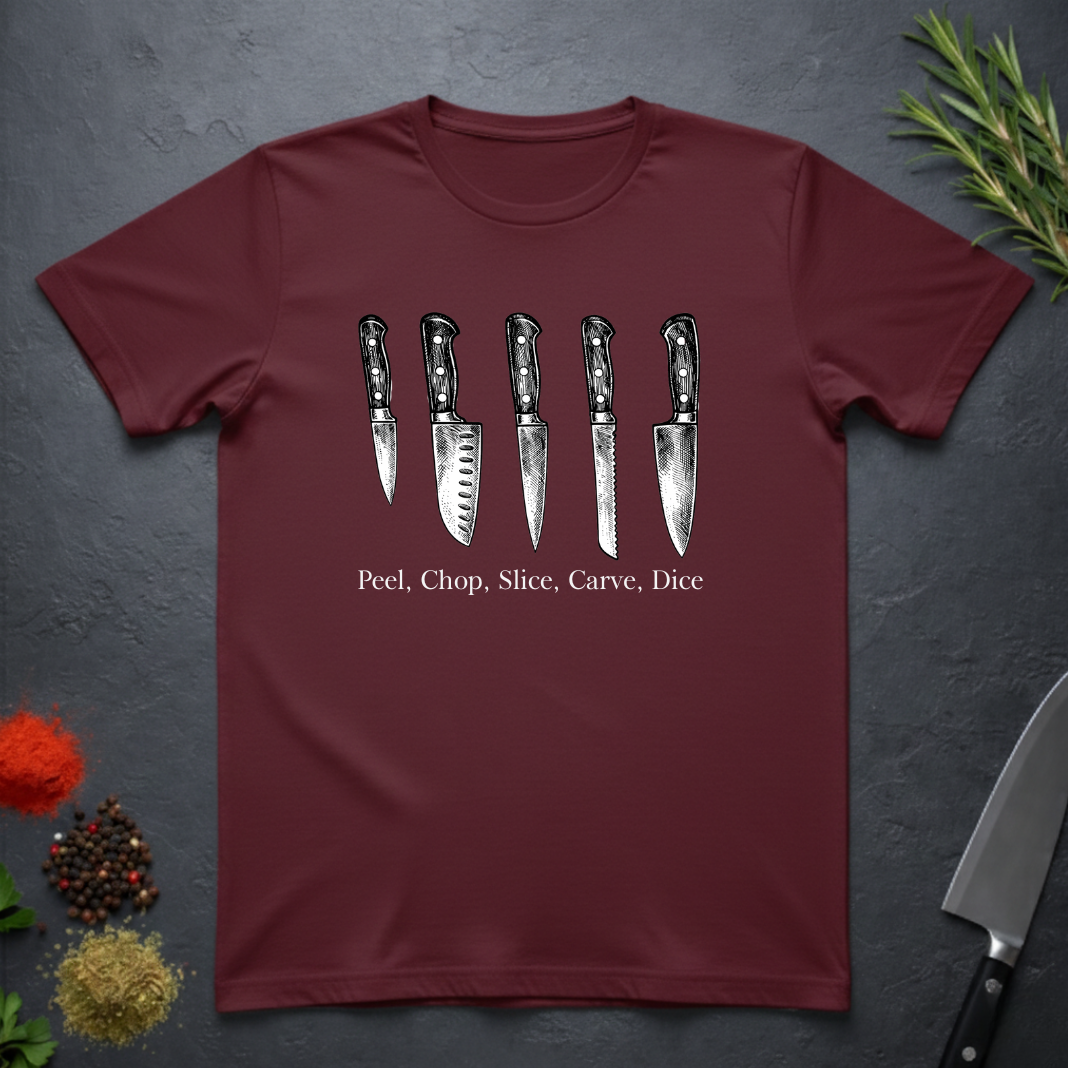Maroon t-shirt with knife graphic and text on a dark surface with kitchen items.