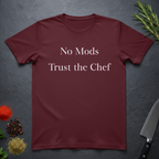 Maroon t-shirt with 'No Mods Trust the Chef' text on a dark surface with kitchen items.
