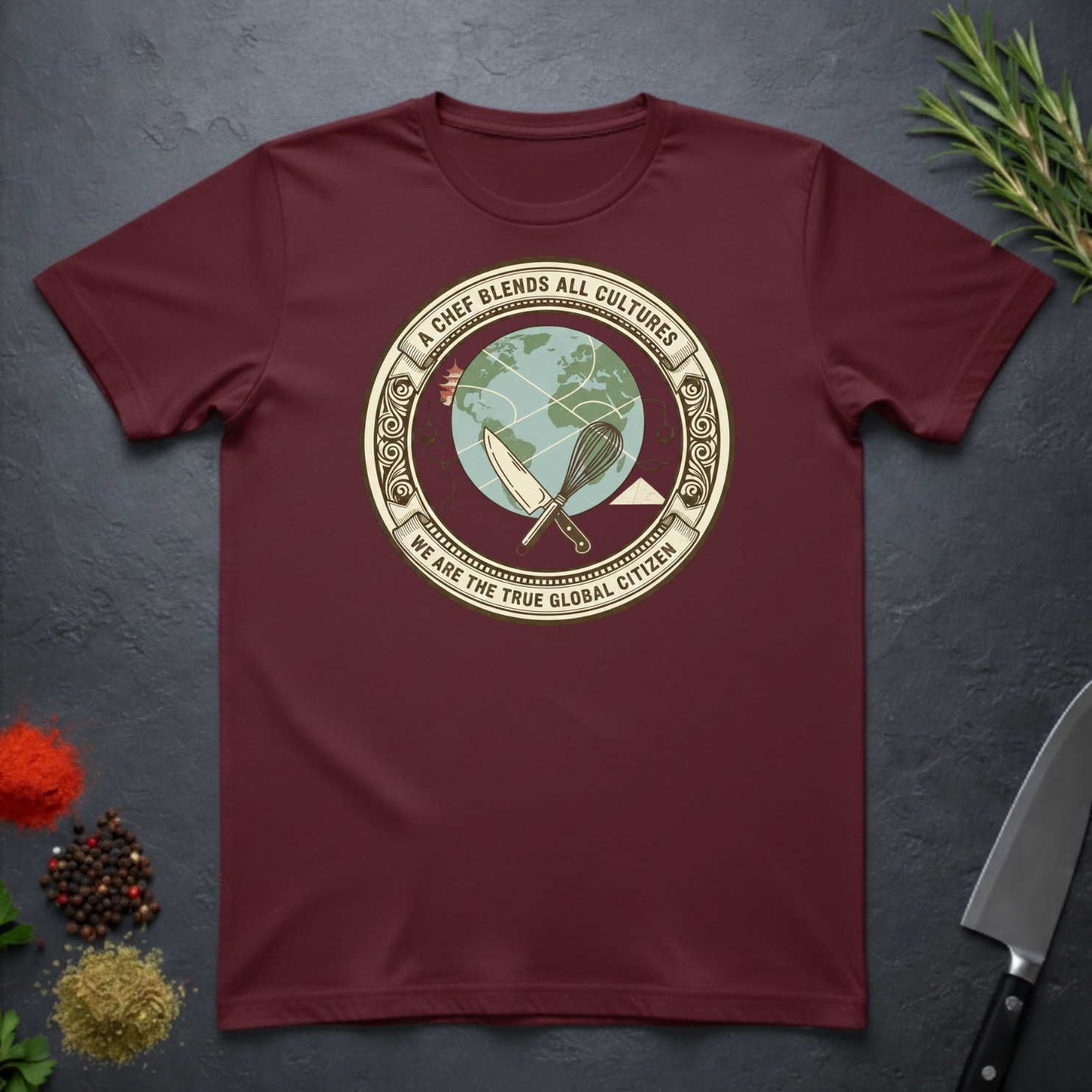 Maroon t-shirt with circular graphic of a globe and text "A Chef Blends All Cultures" on a dark surface.