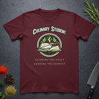 Maroon t-shirt with 'Culinary Student' design on a dark surface with kitchen items.