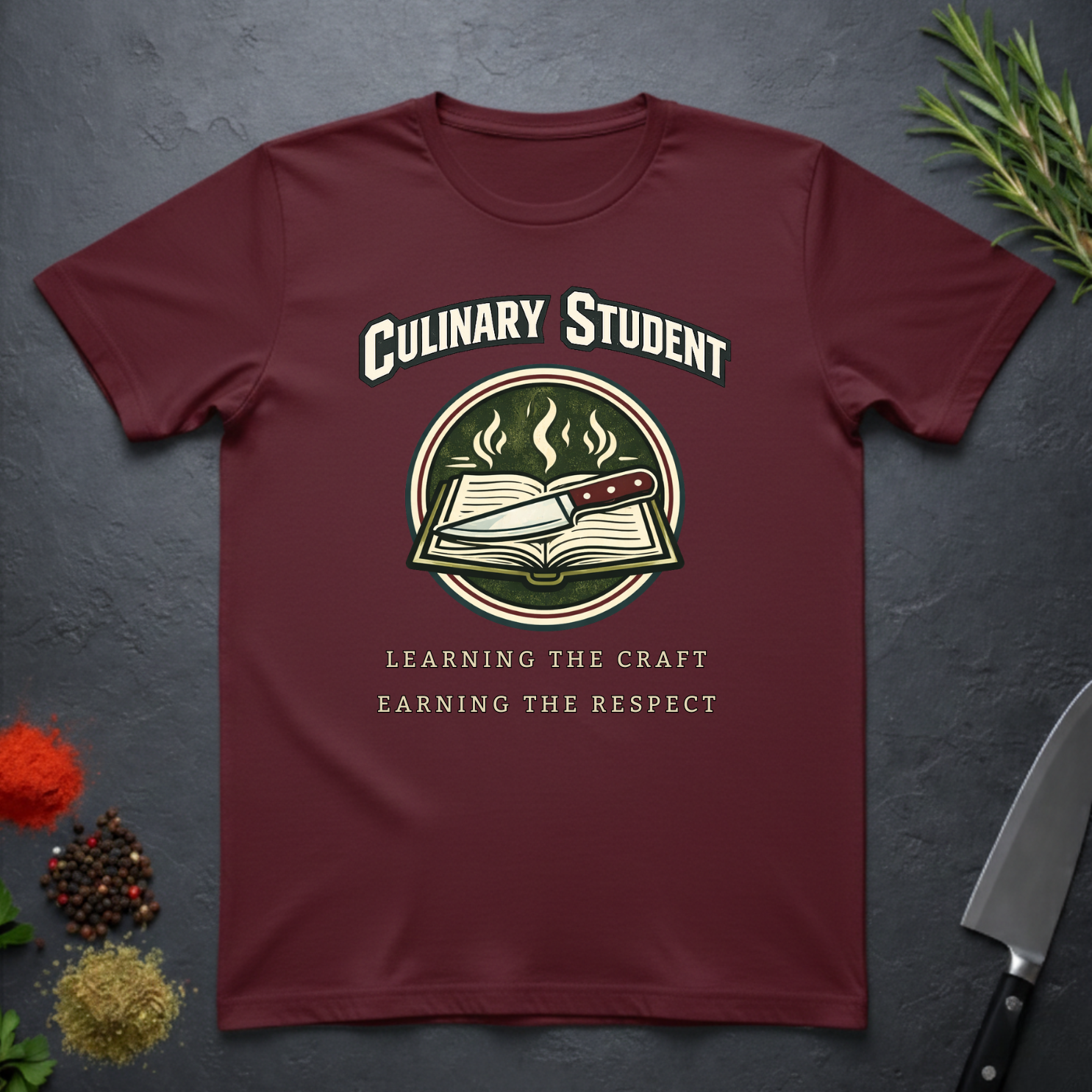 Maroon t-shirt with 'Culinary Student' design on a dark surface with kitchen items.