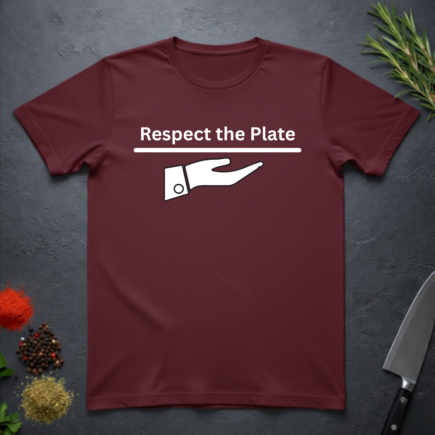Maroon t-shirt with 'Respect the Plate' graphic on a dark surface with kitchen items.
