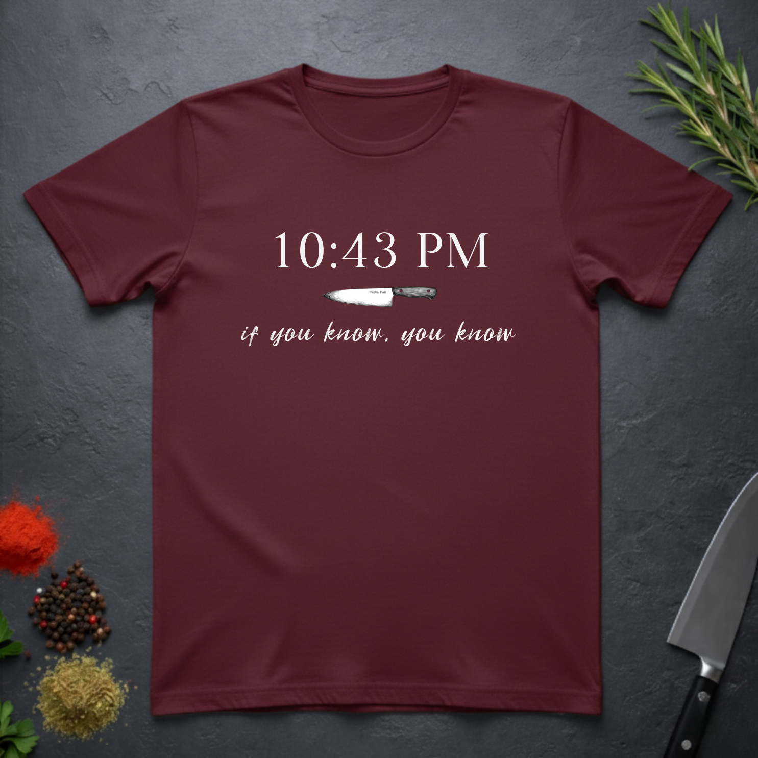 Maroon t-shirt with knife graphic and text "10:43 PM - if you know, you know" on a dark surface.