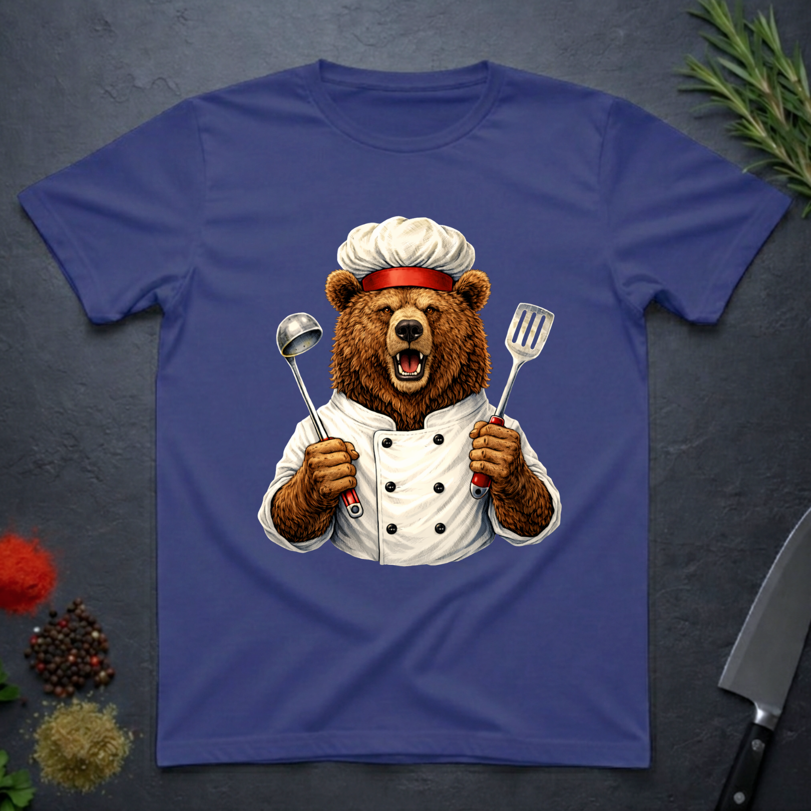 Metro blue t-shirt with a grizzly bear chef holding utensils design on a dark surface.
