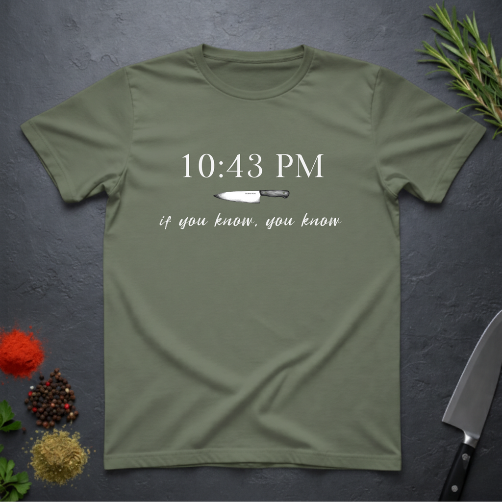 Military green t-shirt with knife graphic and text "10:43 PM - if you know, you know" on a dark surface.