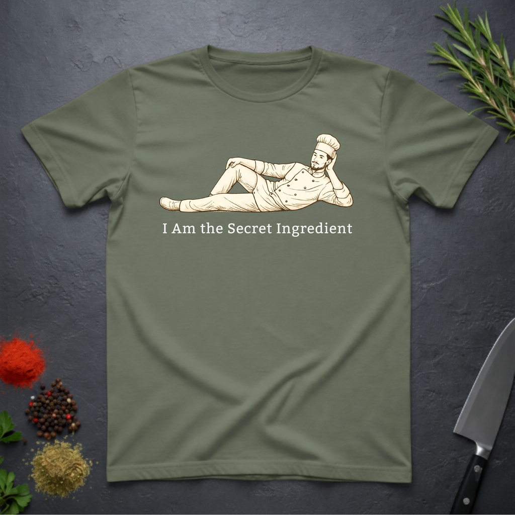 Military Green t-shirt with a graphic of a man lying on side and text 'I Am the Secret Ingredient' on a dark surface.