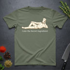 Military Green t-shirt with a graphic of a man lying on side and text 'I Am the Secret Ingredient' on a dark surface.