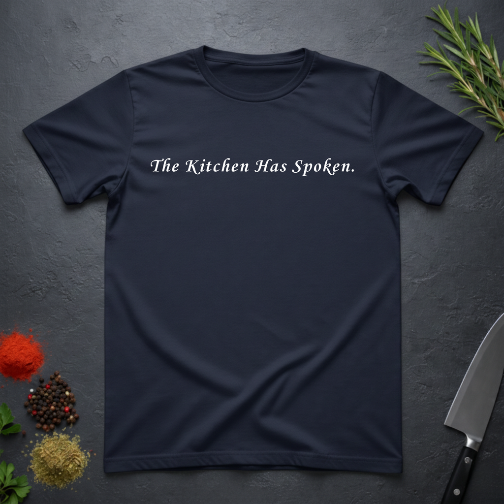 Navy Blue t-shirt with 'The Kitchen Has Spoken.' text on a dark surface with kitchen items.