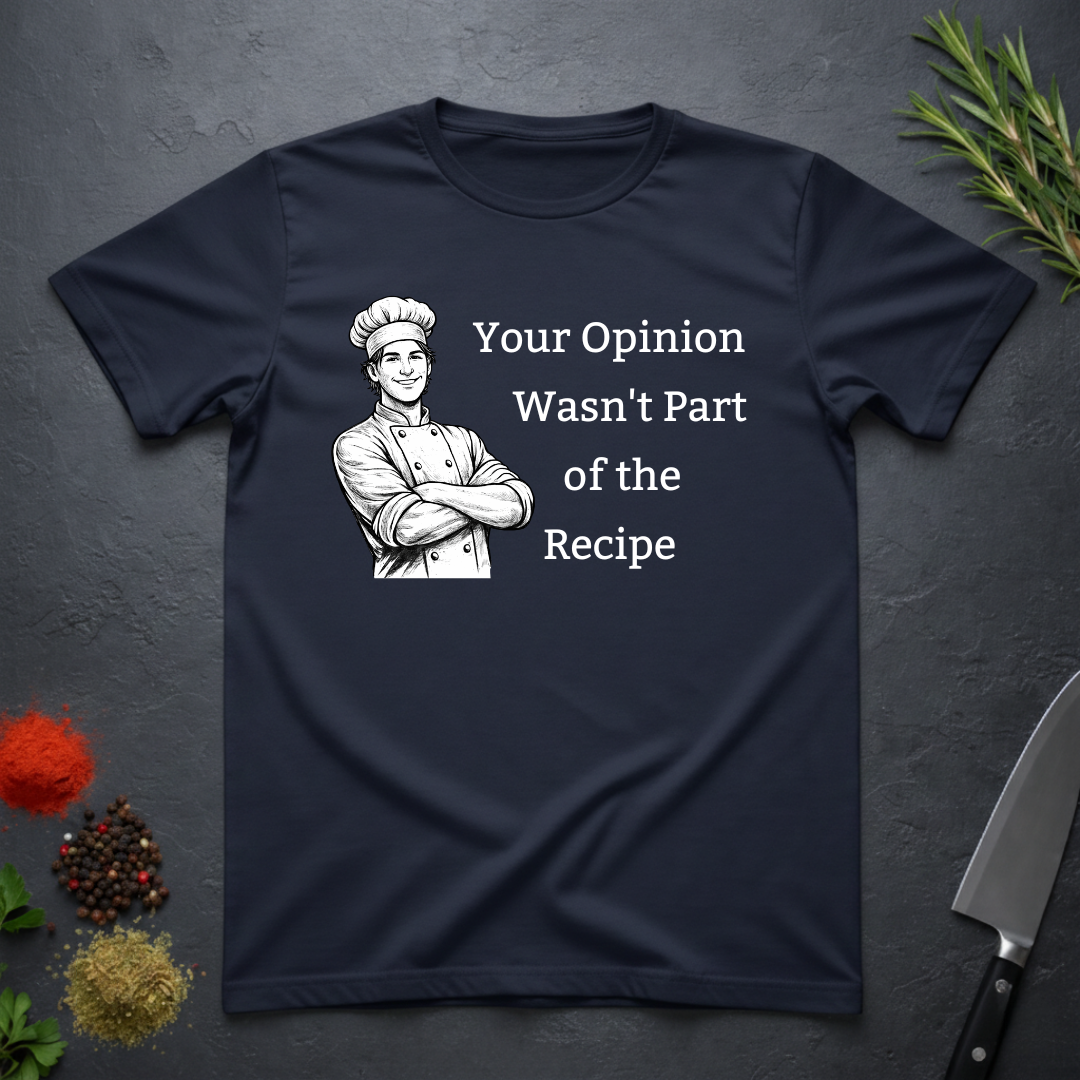 Navy blue t-shirt with a male chef graphic and text "Your Opinion Wasn't Part of the Recipe" on a dark surface with kitchen items.