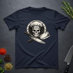 Navy blue t-shirt with skull in chef hat with crossed knifes graphic on a dark surface.