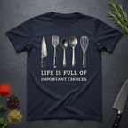 Navy blue t-shirt with kitchen utensil graphics and text "Life is Full of Important Choices" on a dark surface.
