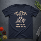Navy blue t-shirt with text "Wine Improves With Age. I Improve With Wine" in an off-white bold font. Image of wine glass and grape bunches separate text. From the Bitter Palate brand.