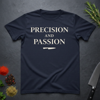 Navy blue t-shirt with 'PRECISION AND PASSION' text on a dark surface with kitchen items.